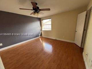 unfurnished bedroom featuring ceiling fan and dark hardwood / wood-style flooring