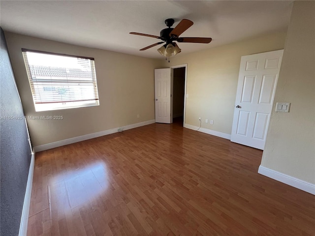 unfurnished bedroom with ceiling fan and dark wood-type flooring