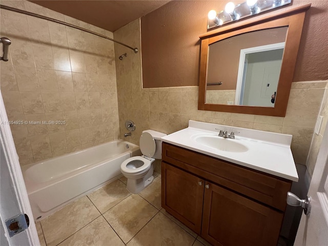 full bathroom with tile patterned flooring, toilet, vanity, tile walls, and tiled shower / bath