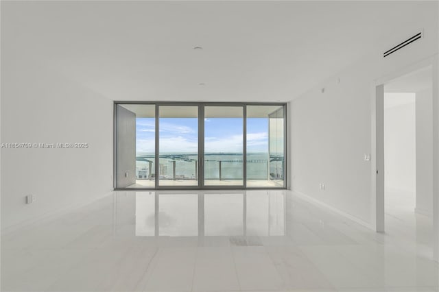 tiled empty room with expansive windows and a water view