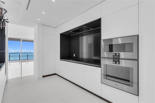 kitchen featuring white cabinets, floor to ceiling windows, a water view, and stainless steel double oven