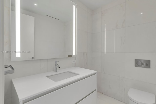 bathroom featuring vanity, toilet, and tile walls