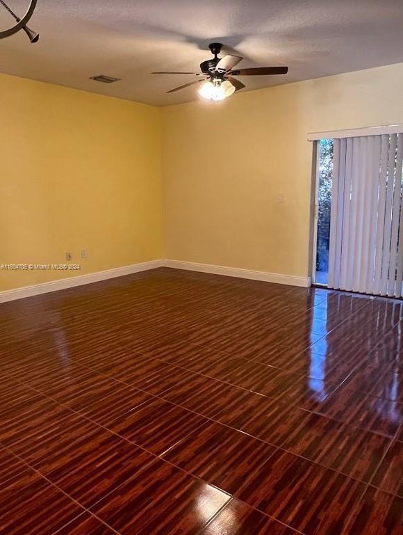 spare room featuring a ceiling fan, baseboards, and dark wood-type flooring