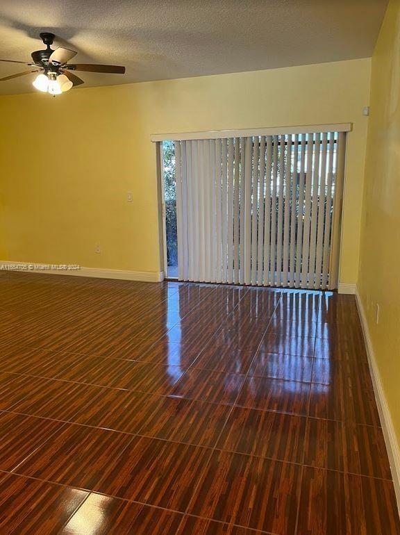 unfurnished room featuring dark hardwood / wood-style flooring, ceiling fan, and a textured ceiling