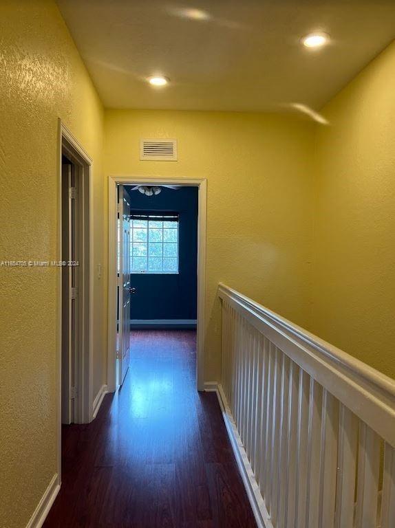hall with wood finished floors, recessed lighting, and a textured wall