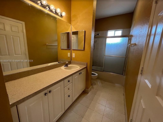 bathroom with tile patterned floors, vanity, toilet, and shower / bath combination with glass door