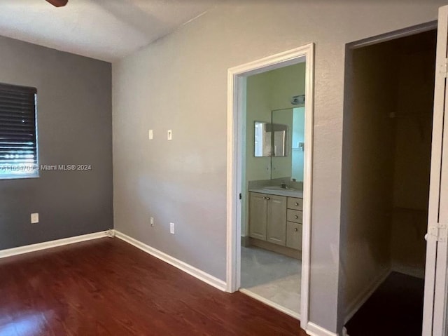 unfurnished bedroom featuring dark wood-type flooring, ceiling fan, ensuite bathroom, and sink