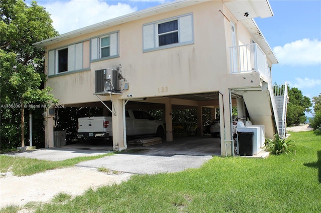 rear view of property with a yard, a carport, and central air condition unit