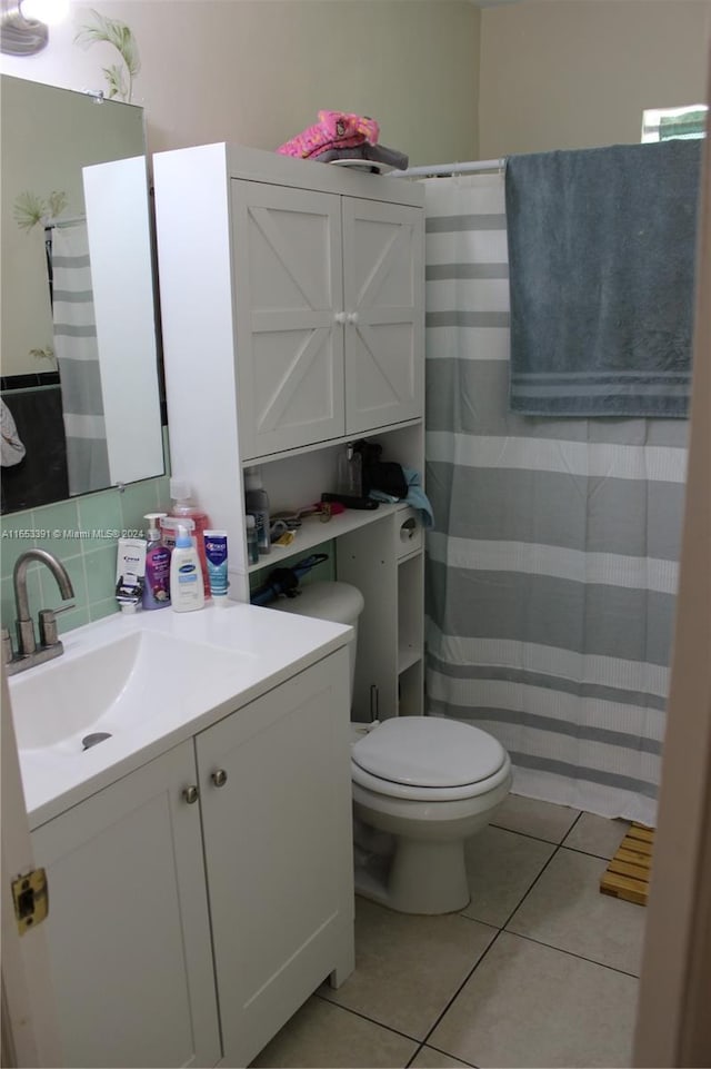 bathroom featuring vanity, toilet, tile patterned floors, and tasteful backsplash