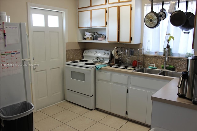 kitchen with white appliances, a sink, light tile patterned floors, white cabinets, and decorative backsplash