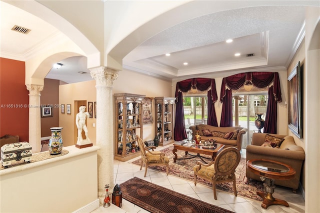 tiled living room with a textured ceiling, a raised ceiling, crown molding, and ornate columns