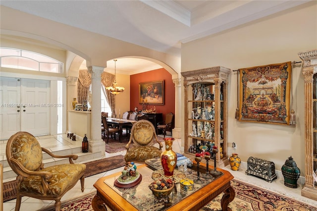 living room featuring a notable chandelier, crown molding, ornate columns, and tile patterned floors