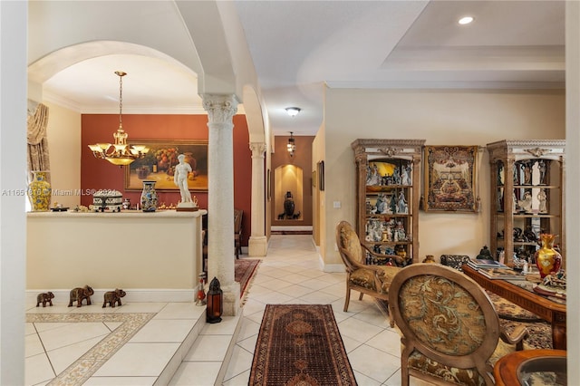 tiled entryway featuring a notable chandelier, decorative columns, and crown molding