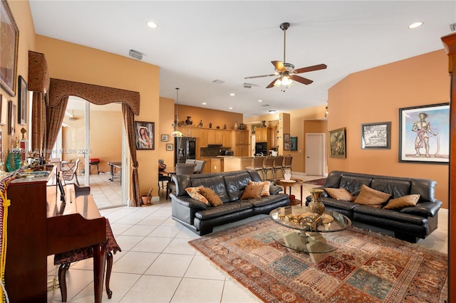 living room featuring lofted ceiling, light tile patterned flooring, and ceiling fan