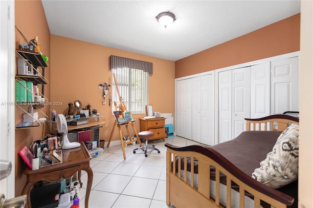 bedroom featuring multiple closets, a textured ceiling, and light tile patterned flooring