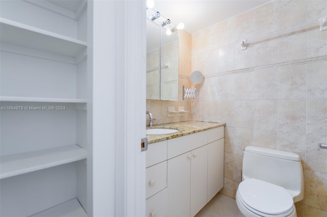 bathroom with vanity, toilet, and tile walls