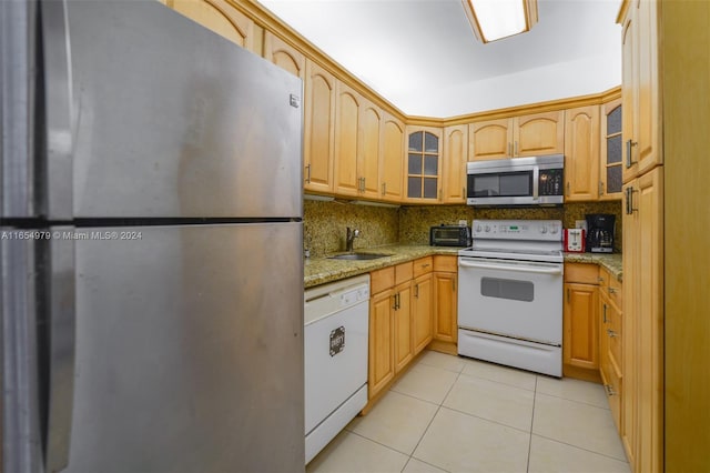 kitchen featuring backsplash, light tile patterned floors, light stone countertops, stainless steel appliances, and sink