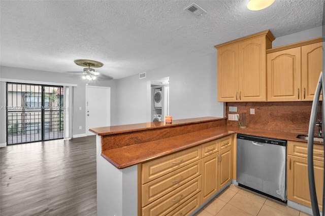 kitchen with dishwasher, light wood-type flooring, stacked washer and dryer, kitchen peninsula, and ceiling fan