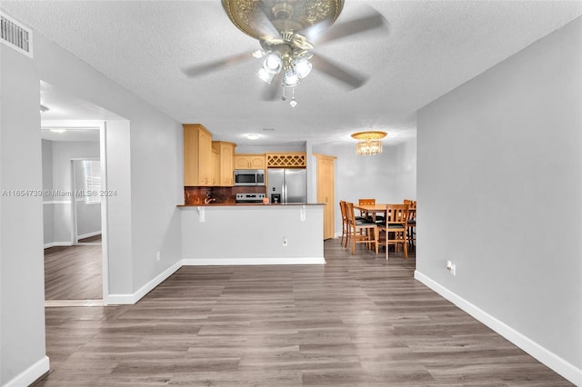 kitchen with hardwood / wood-style floors, appliances with stainless steel finishes, kitchen peninsula, ceiling fan, and a textured ceiling