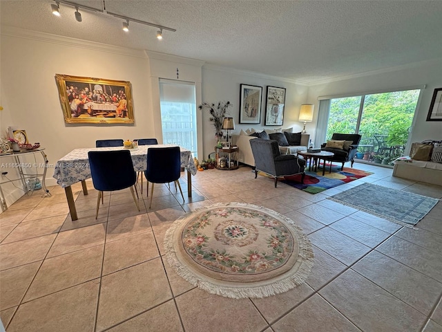 dining area with a textured ceiling, rail lighting, ornamental molding, and light tile patterned floors