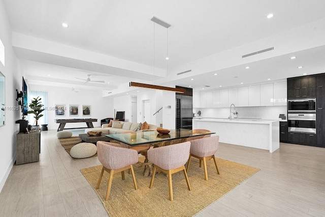 dining area with ceiling fan, sink, and light hardwood / wood-style floors