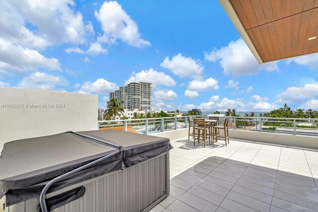 view of patio with a balcony and a hot tub