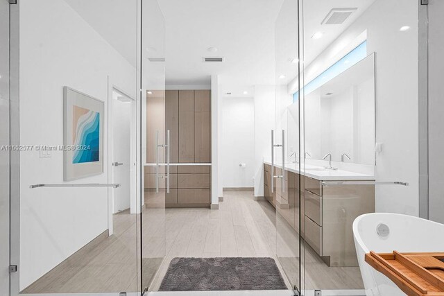 bathroom featuring vanity, a bath, and wood-type flooring