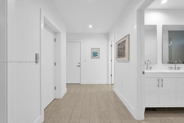 hallway featuring sink and light hardwood / wood-style floors