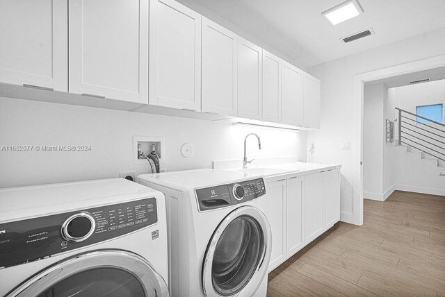 laundry room featuring light wood-type flooring, cabinets, independent washer and dryer, and sink