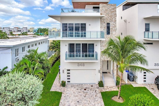 348 Desoto St, Hollywood, FL 33019 - view of front of house with stucco siding, stone siding, an attached garage, and driveway