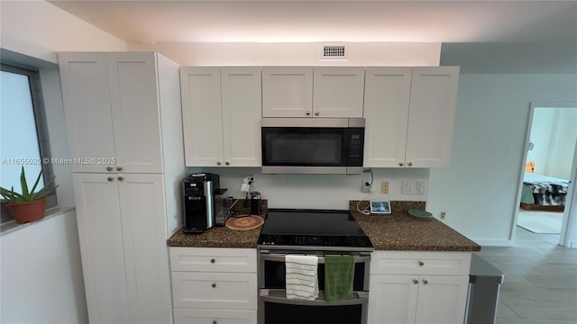 kitchen with white cabinets, dark stone counters, and appliances with stainless steel finishes