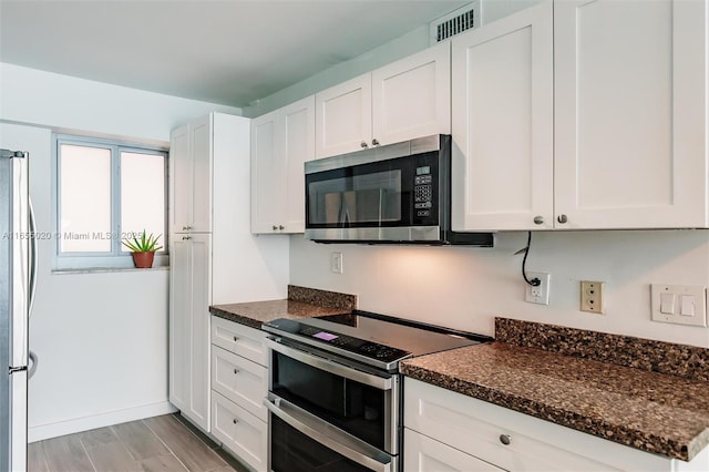 kitchen with white cabinets, dark stone countertops, and appliances with stainless steel finishes