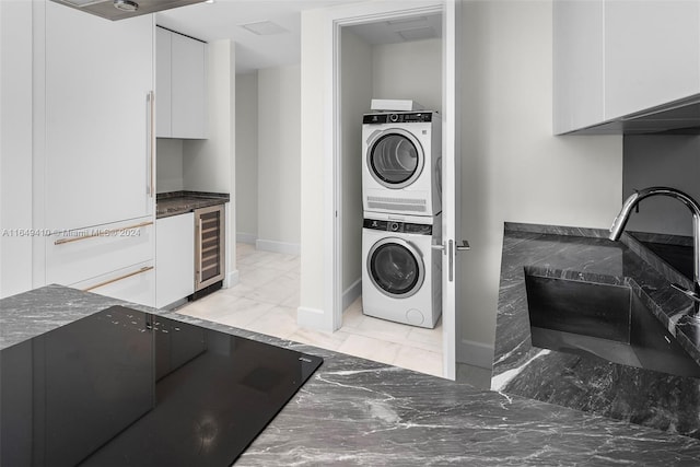 washroom featuring stacked washer / dryer, wine cooler, and sink