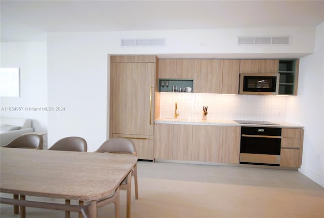 kitchen featuring appliances with stainless steel finishes, decorative backsplash, and light brown cabinetry