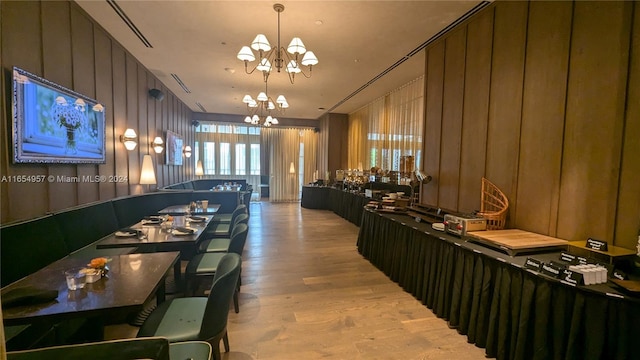 interior space featuring an inviting chandelier, light hardwood / wood-style flooring, and wooden walls