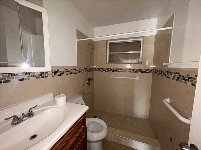 bathroom featuring toilet, a tile shower, tile walls, and vanity