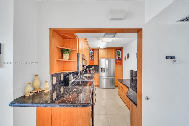 kitchen with kitchen peninsula, backsplash, dark stone counters, stainless steel appliances, and light tile patterned flooring