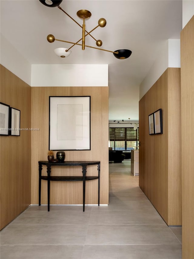 corridor featuring wooden walls and a notable chandelier