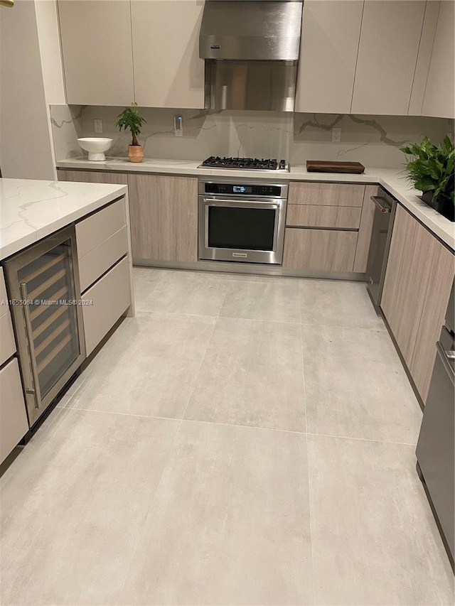 kitchen with appliances with stainless steel finishes, light stone counters, backsplash, and wall chimney exhaust hood