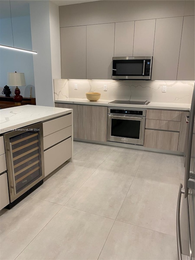 kitchen featuring light tile patterned floors, light stone counters, stainless steel appliances, wine cooler, and decorative backsplash