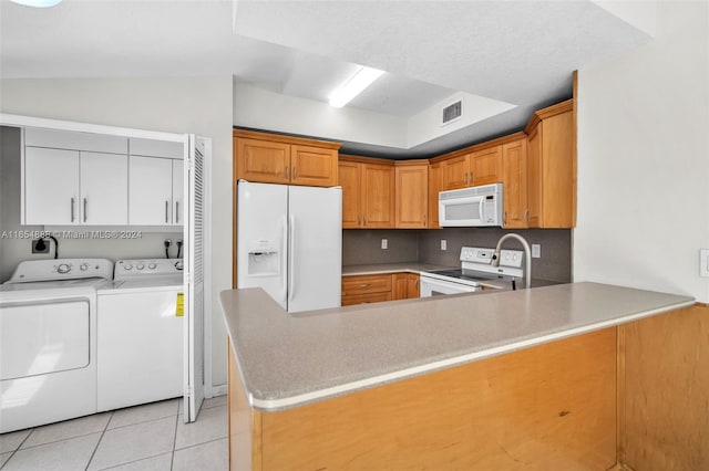 kitchen with kitchen peninsula, separate washer and dryer, light tile patterned floors, and white appliances