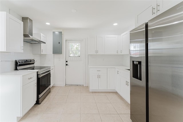 kitchen with appliances with stainless steel finishes, white cabinetry, and wall chimney range hood