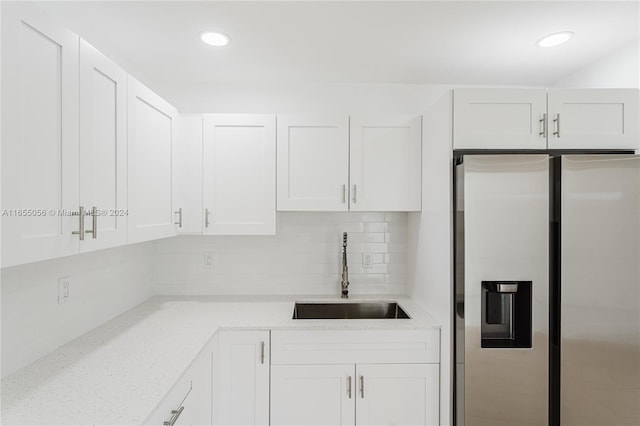 5847 Mayo St, Hollywood, FL 33023 - kitchen featuring stainless steel fridge with ice dispenser, a sink, white cabinetry, decorative backsplash, and light stone countertops