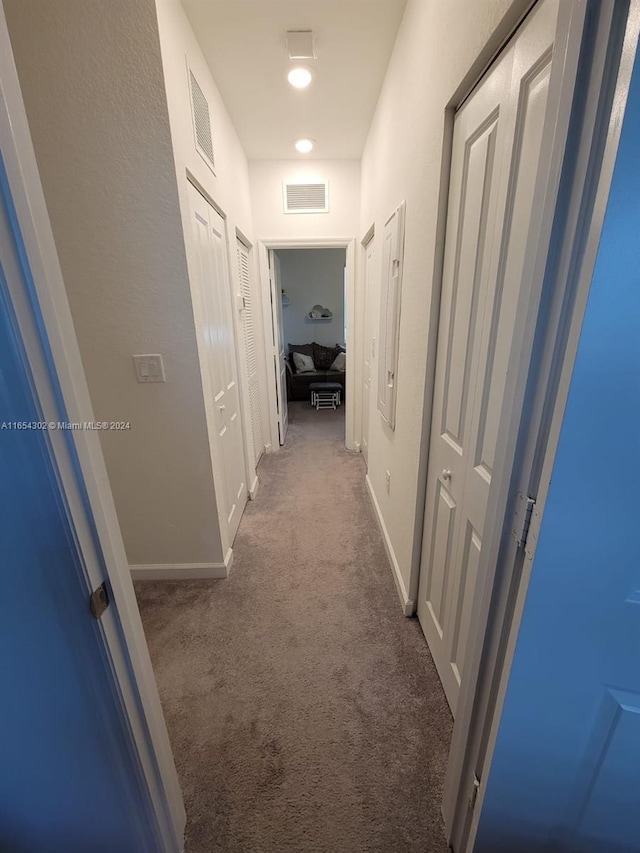 hall featuring baseboards, visible vents, and carpet floors