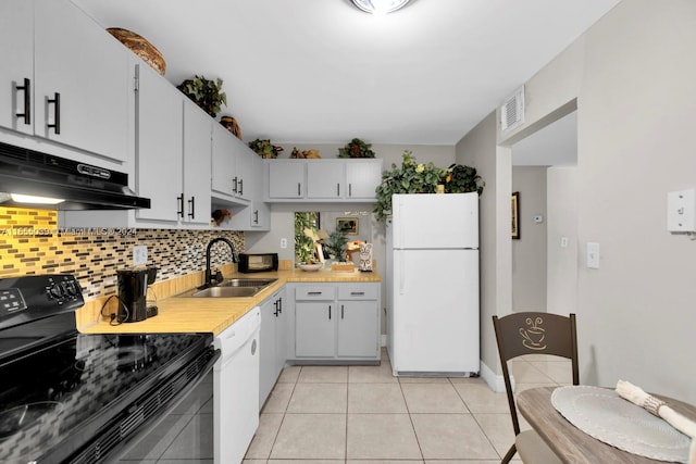 kitchen with light tile patterned flooring, sink, white appliances, backsplash, and white cabinetry