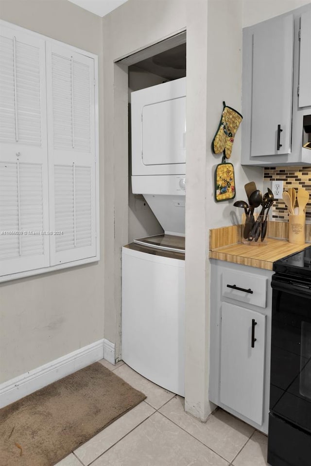 washroom with stacked washer and dryer and light tile patterned floors