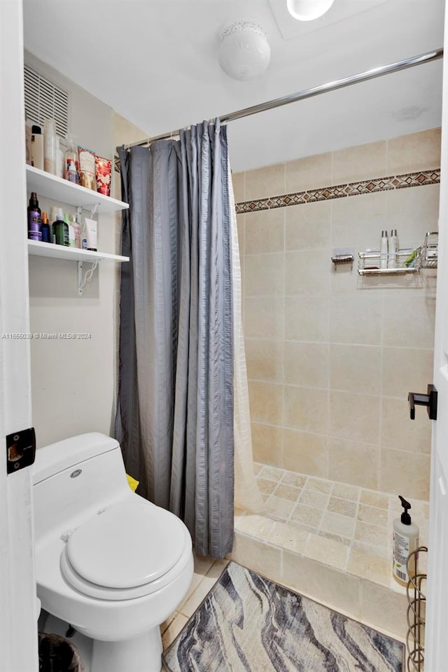 bathroom featuring tile patterned flooring, toilet, and curtained shower