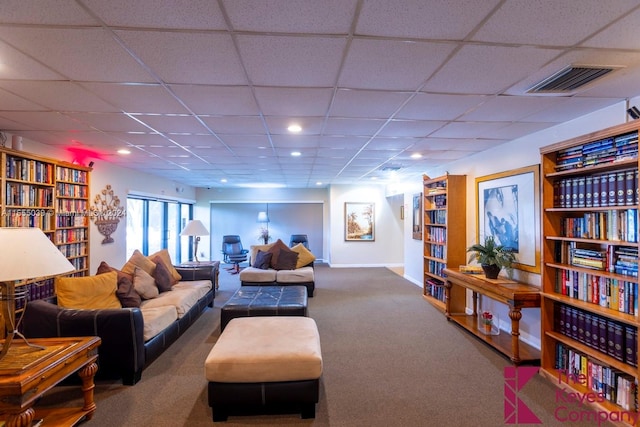 living room featuring a drop ceiling and carpet floors