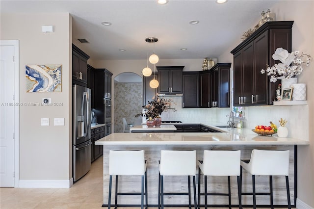 kitchen featuring appliances with stainless steel finishes, kitchen peninsula, sink, and a breakfast bar