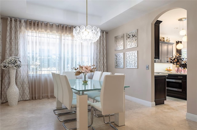 dining space featuring a healthy amount of sunlight, a notable chandelier, and a tray ceiling